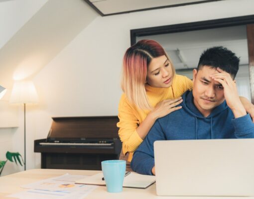 young stressed asian couple managing finances reviewing their bank accounts using laptop computer 7861 1048